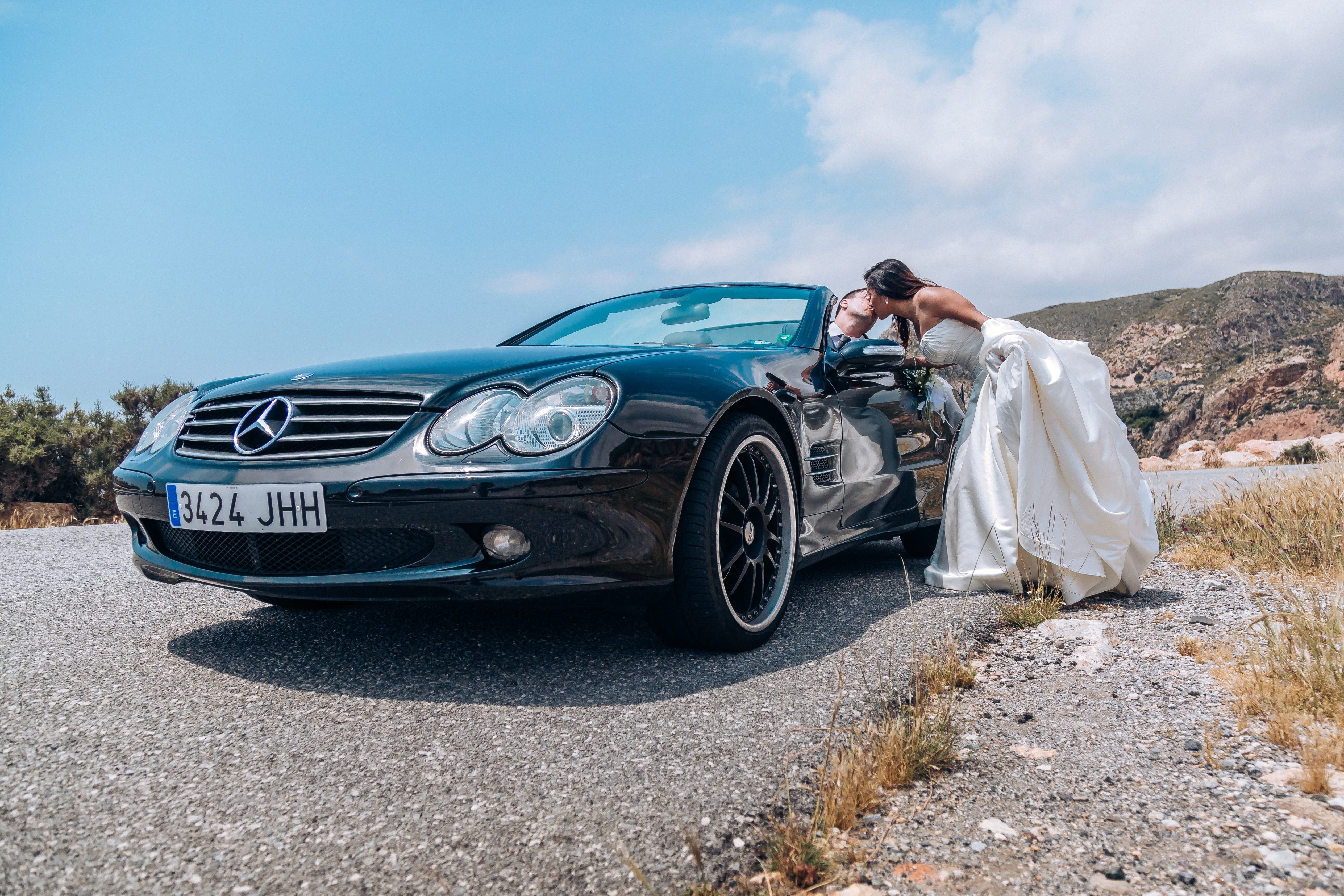 Boda de Verano, el la novia da un beso al novio montado en un coche clásico mercedes, sin posados