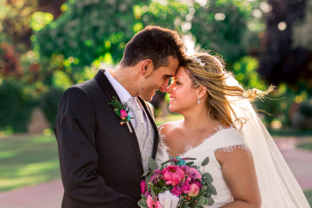 Retrato de novios con el ramo entre ellos mirándose y sonriendo